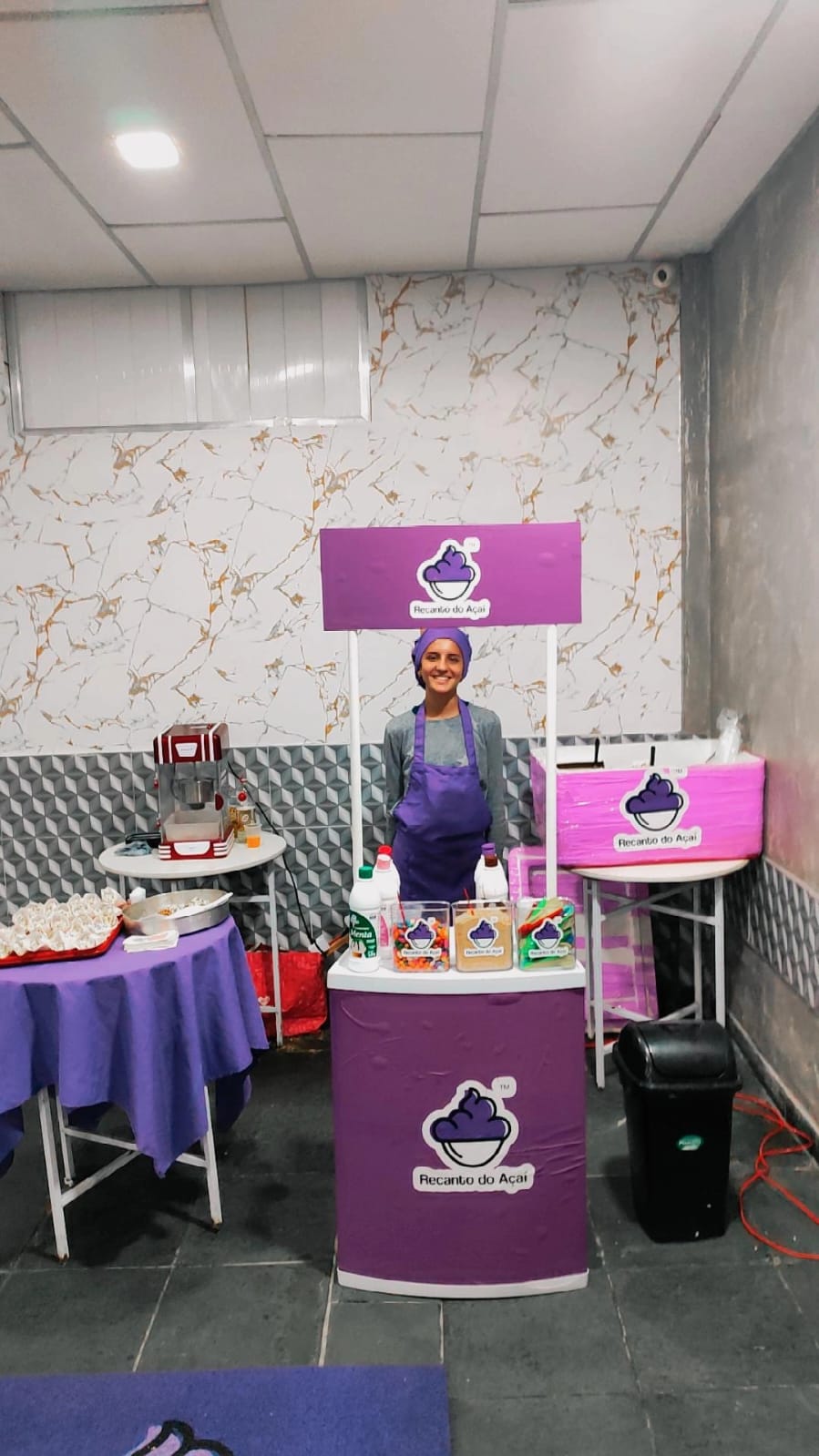 Atendente uniformizada operando a estação de açaí em um salão de festas